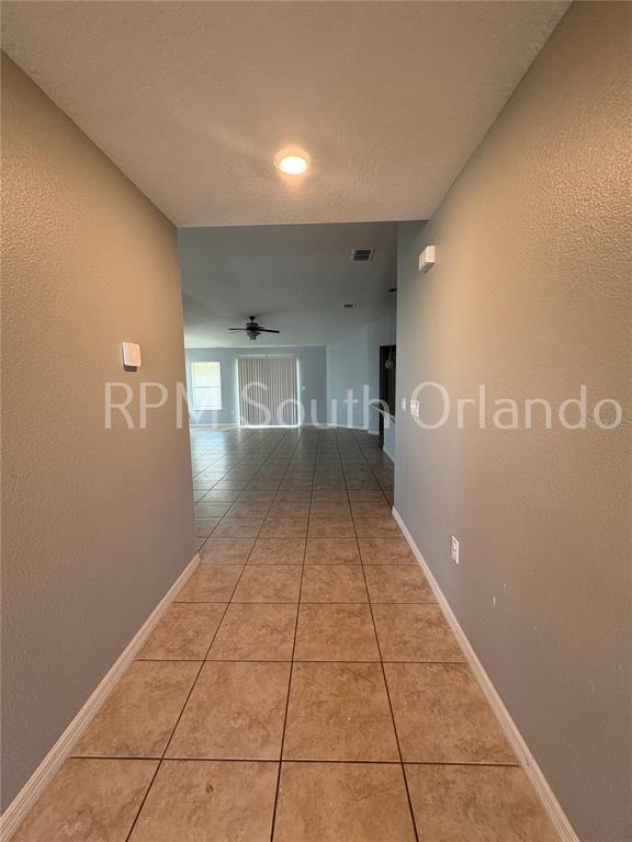 A tiled hallway leads into an open living area with a ceiling fan and sliding doors — 4751 MAPLEWILD LANE, ST CLOUD, FL