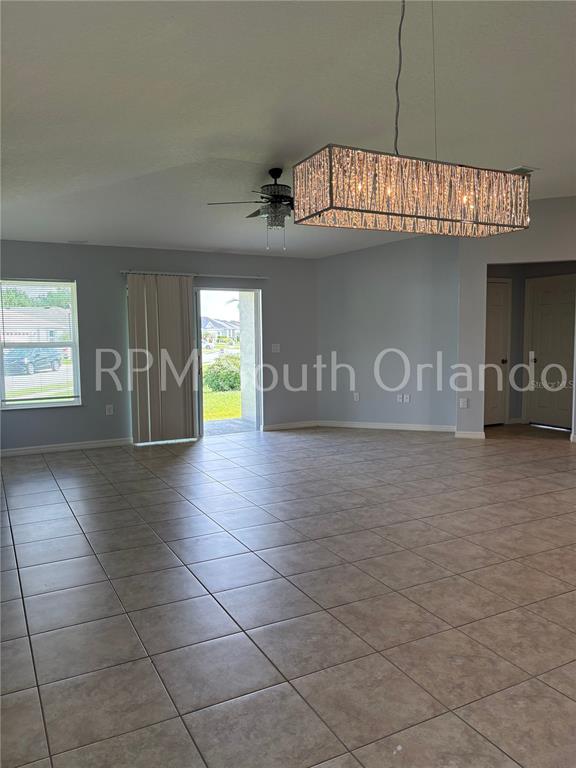 An open living area features tile flooring, a rectangular chandelier, and a sliding glass door — 4751 MAPLEWILD LANE, ST CLOUD, FL