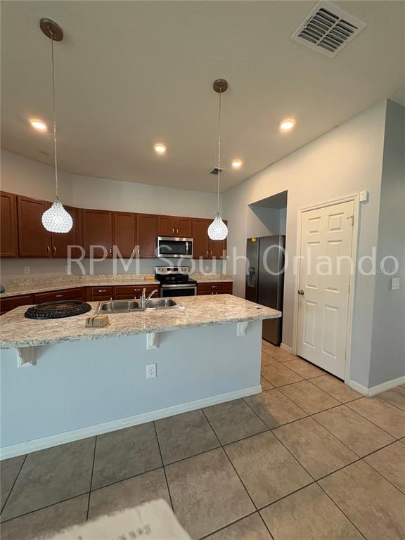 A kitchen features wood cabinets, granite countertops, a central island, and stainless steel appliances — 4751 MAPLEWILD LANE, ST CLOUD, FL