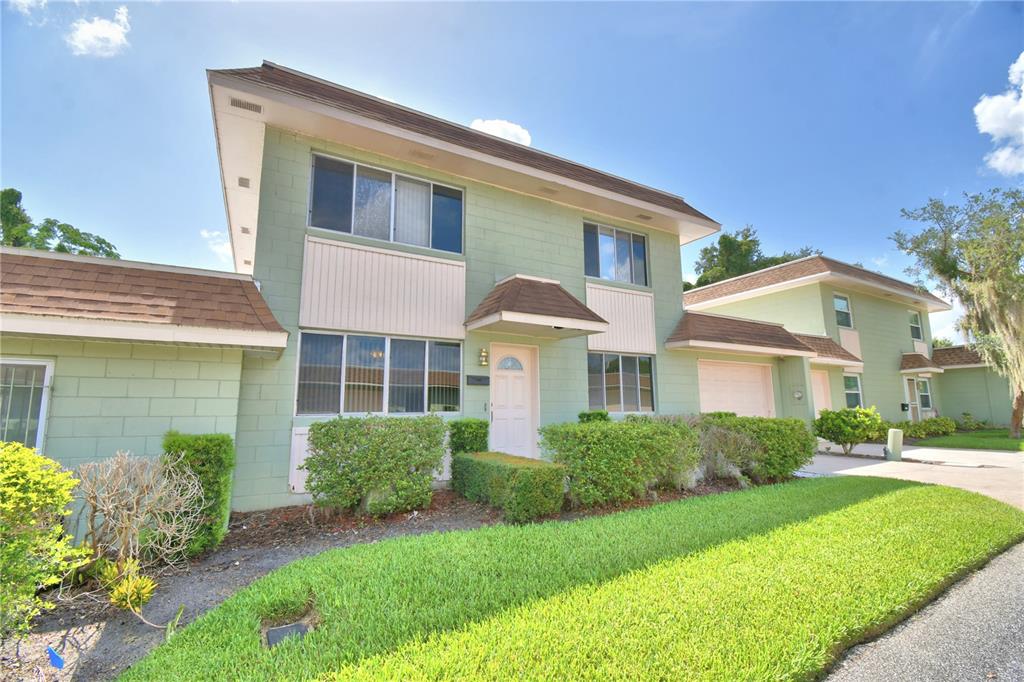 A two-story green concrete block townhouse with a brown shingled roof and front landscaping — 2216 STARBOARD, WINTER HAVEN, FL