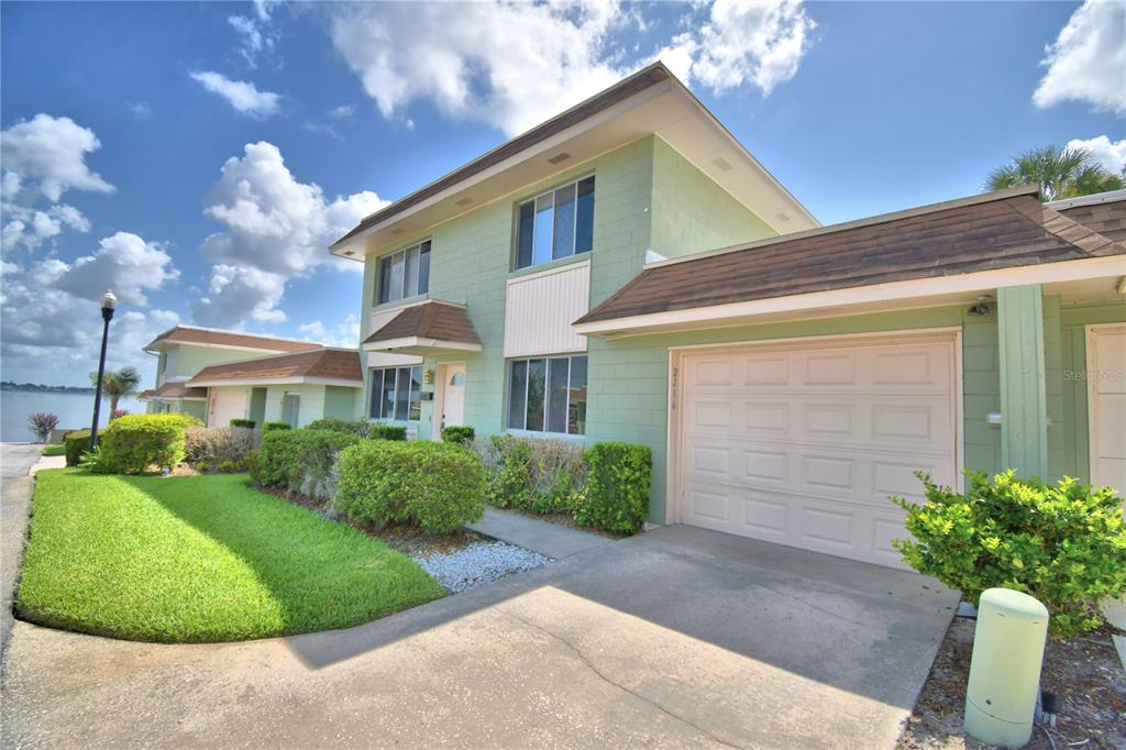 A two-story light green house with a garage and a view of the water — 2216 STARBOARD, WINTER HAVEN, FL