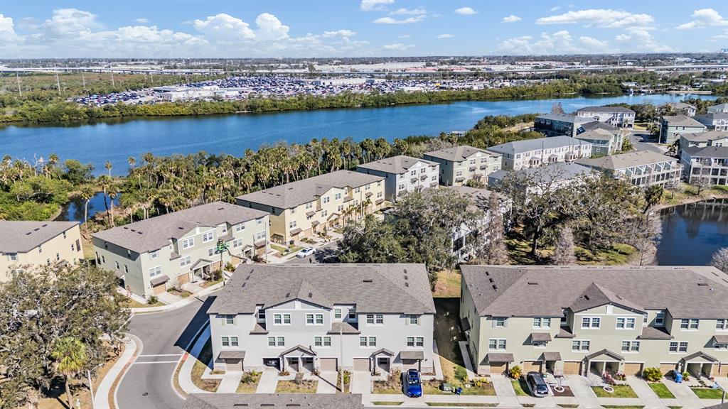 An aerial view shows multi-story townhomes situated near a body of water and parking lots — 4607 TUSCAN LOON DRIVE, TAMPA, FL