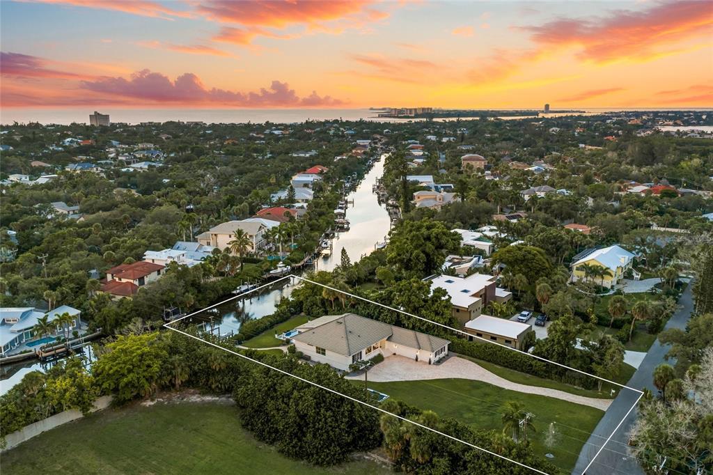 An aerial view shows a single-story house with a large lawn situated along a canal — 5178 OAKMONT PLACE, SARASOTA, FL