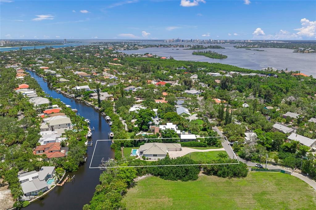 An aerial view shows a waterfront house with a pool and large yard along a canal — 5178 OAKMONT PLACE, SARASOTA, FL
