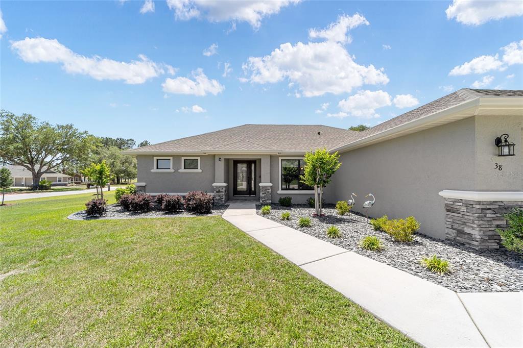 A single-story house features a gray stucco exterior, stone accents, and a concrete walkway — 38 S POLESTAR POINT, INVERNESS, FL