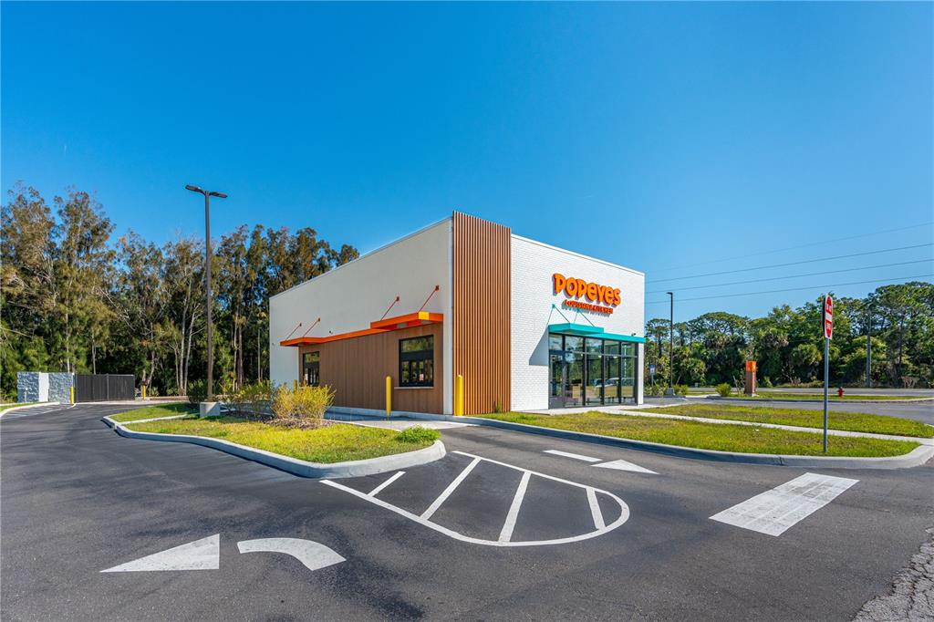 A modern Popeyes restaurant building stands in a parking lot under a clear blue sky — 2900 S RIDGEWOOD AVENUE, EDGEWATER, FL