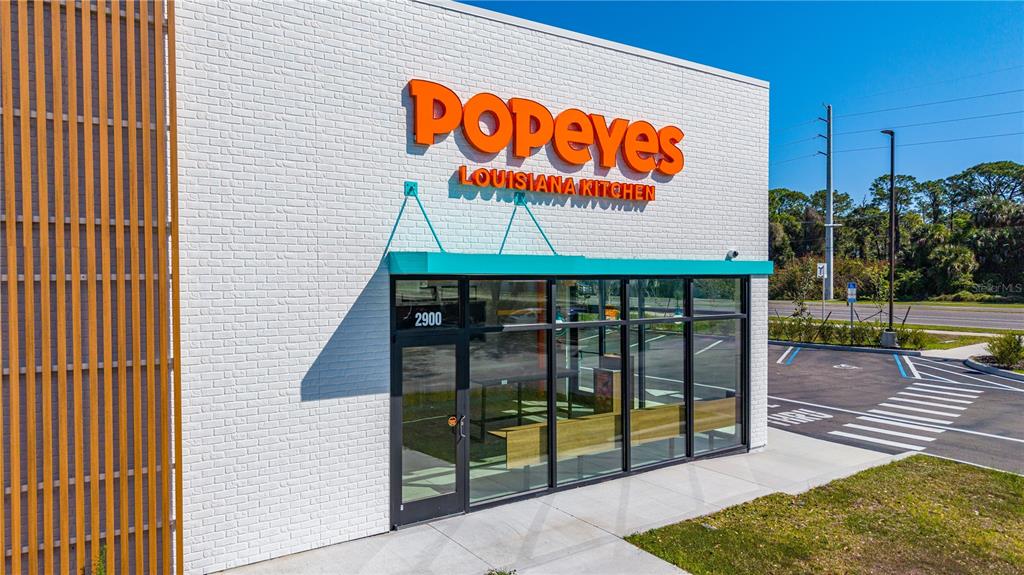The exterior of a modern Popeyes restaurant features white brick walls and a teal awning — 2900 S RIDGEWOOD AVENUE, EDGEWATER, FL