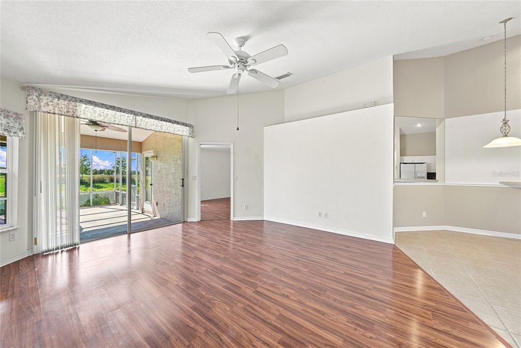 A living room with wood-look flooring, a ceiling fan, and sliding glass doors to a lanai — 4214 FAIRWAY PLACE, NORTH PORT, FL