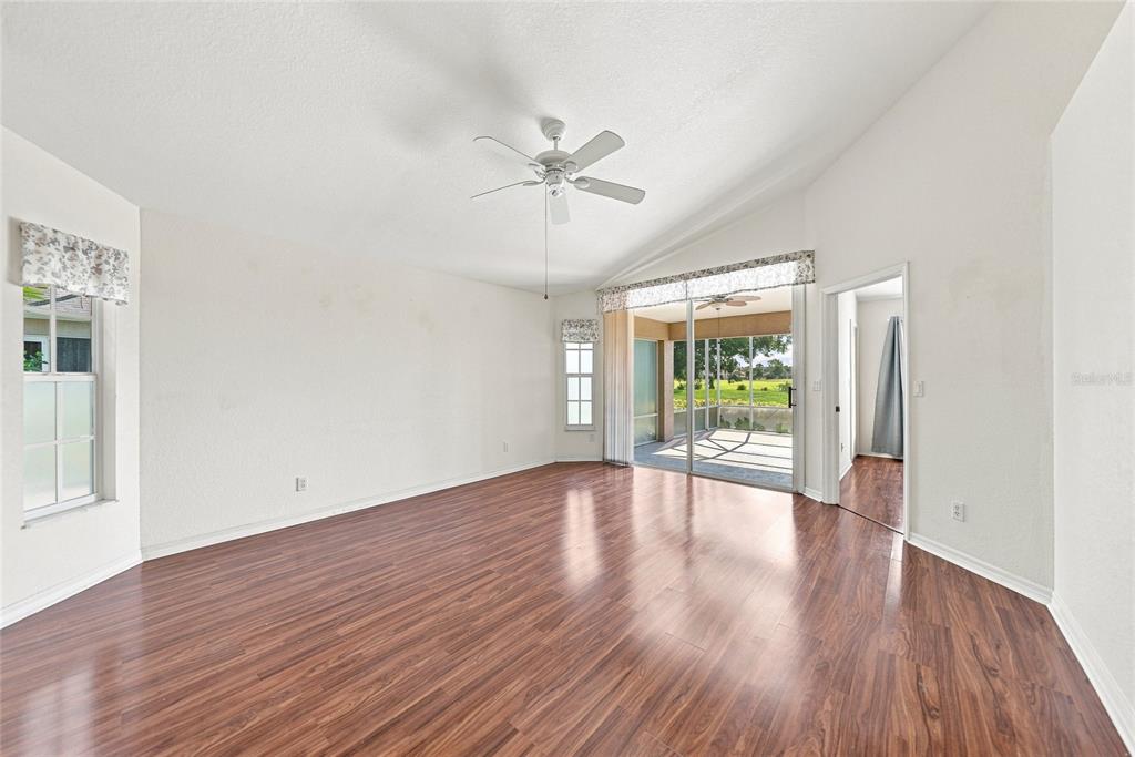 An empty living room features wood-look flooring, a ceiling fan, and sliding glass doors — 4214 FAIRWAY PLACE, NORTH PORT, FL