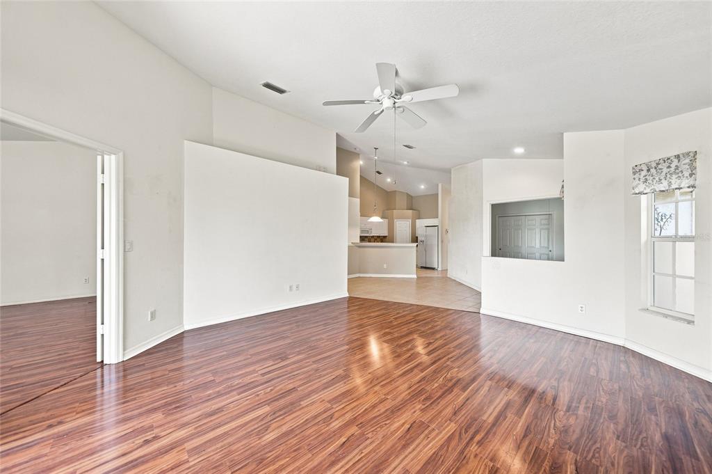 A living room with wood-look flooring, vaulted ceilings, and an adjacent kitchen area — 4214 FAIRWAY PLACE, NORTH PORT, FL