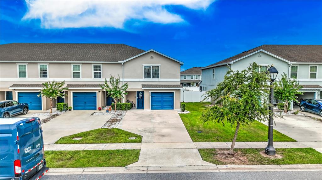 A row of two-story townhomes with blue garage doors and a grassy front yard — 2933 FIELDWOOD CIRCLE, ST CLOUD, FL
