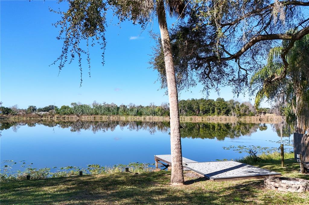A wooden dock extends into a calm lake surrounded by trees under a clear sky — 264 S CENTRAL AVENUE, UMATILLA, FL