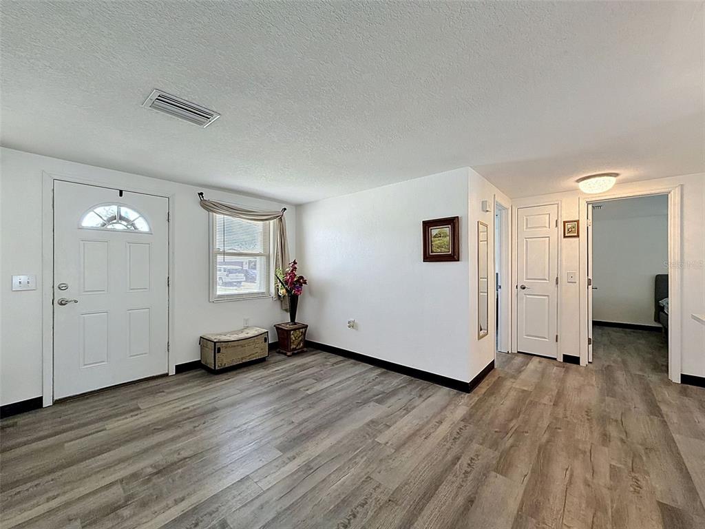 A room with light wood-look flooring, white walls, a front door, and two interior doorways — 12735 1ST ISLE, HUDSON, FL