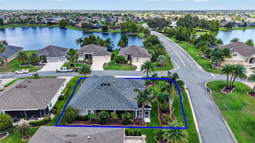 An aerial view shows a single-story house with a screened lanai and landscaped yard — 3992 NEIGHBORLY WAY, THE VILLAGES, FL