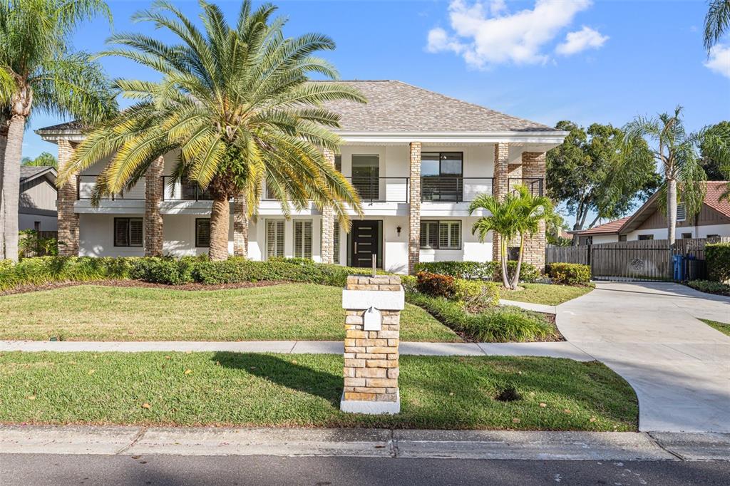 A two-story house with a stone-accented facade, a balcony, and a palm-lined front lawn — 4213 DEEPWATER LANE, TAMPA, FL