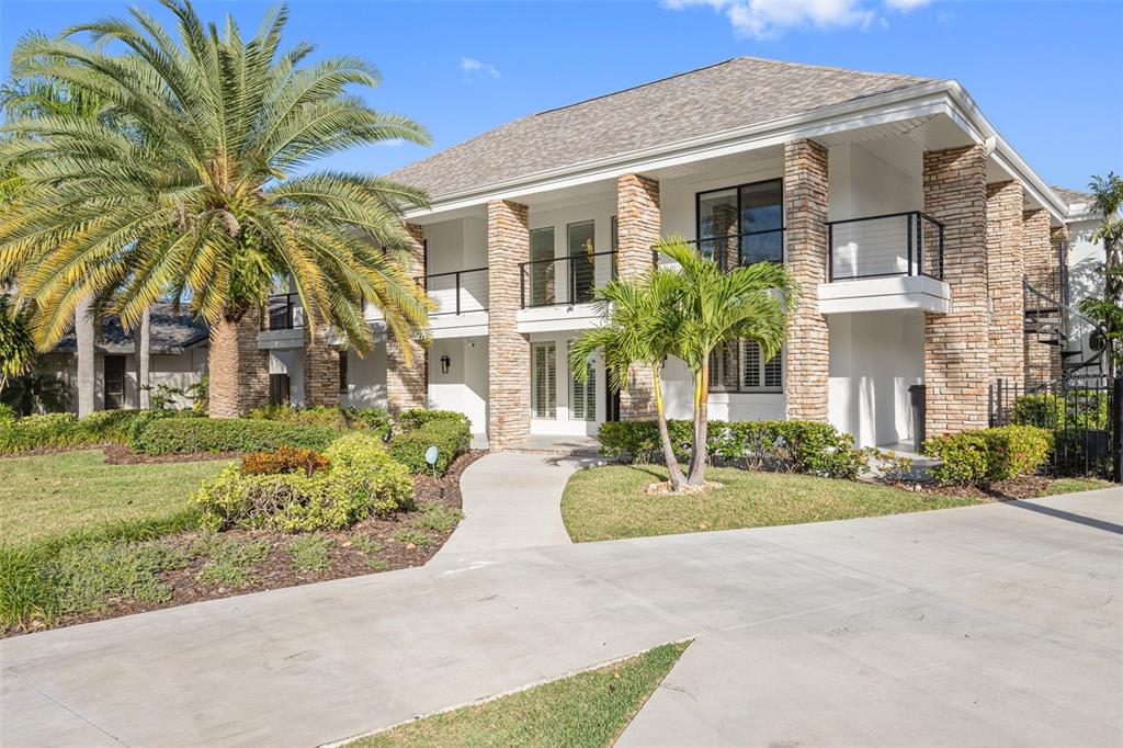 A two-story house with a stone facade, balconies, and a palm tree in the front yard — 4213 DEEPWATER LANE, TAMPA, FL