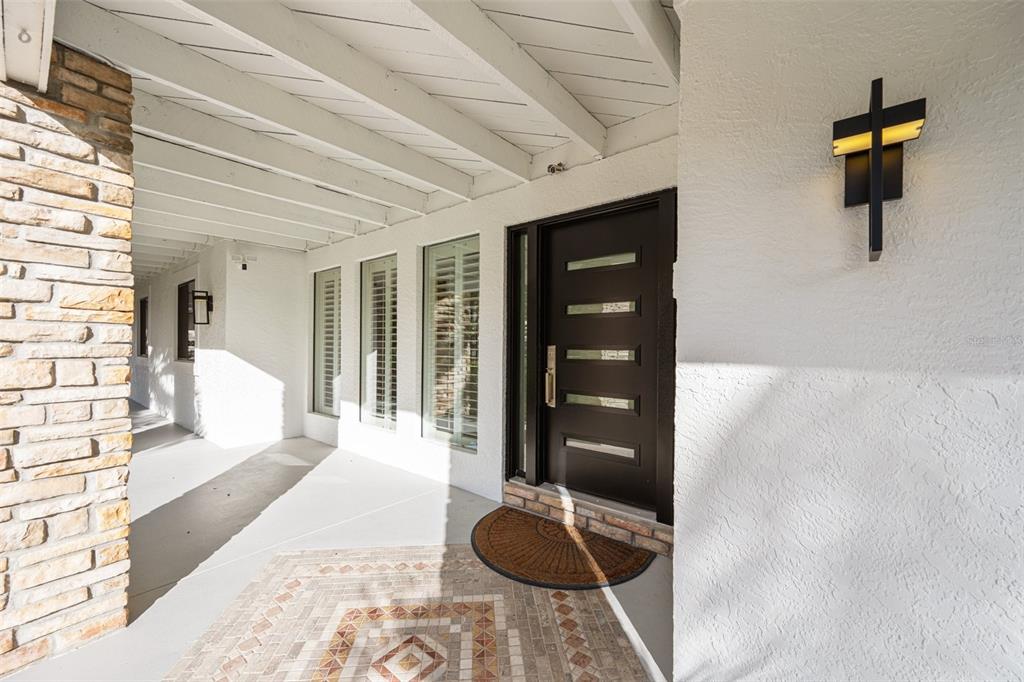 A covered entryway features a dark front door, stone pillar, and patterned tile flooring — 4213 DEEPWATER LANE, TAMPA, FL