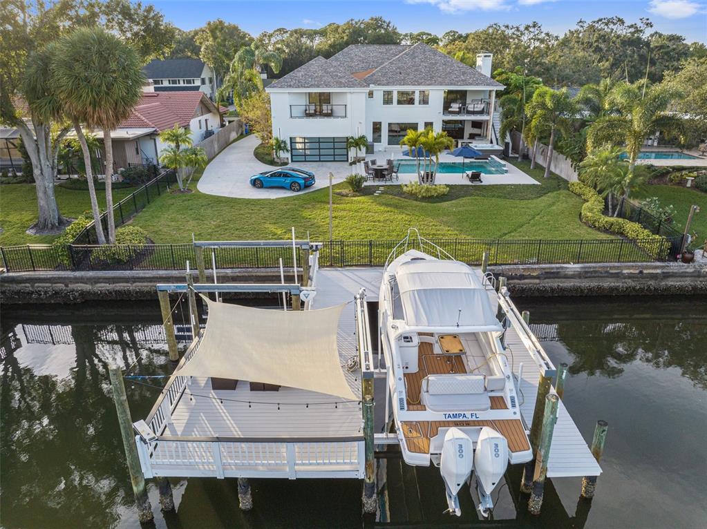 An aerial view shows a waterfront house with a pool, a sports car, and a boat — 4213 DEEPWATER LANE, TAMPA, FL