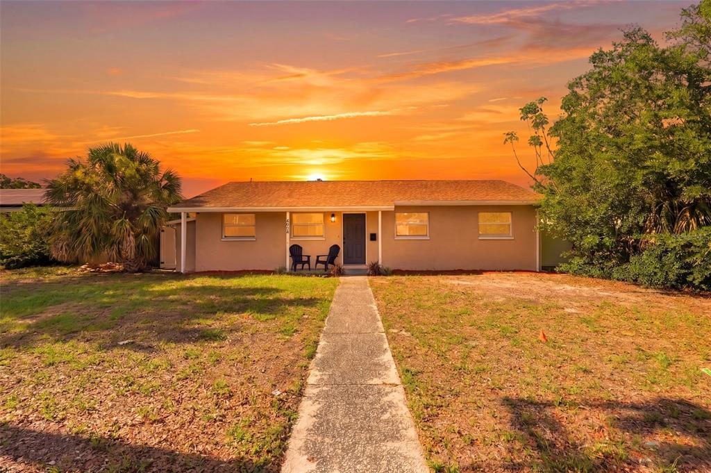A house exterior features a concrete driveway, a covered carport, and a grassy backyard at sunset — 4075 38TH AVENUE N, ST PETERSBURG, FL