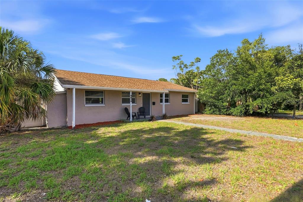 A single-story house with a tan exterior, brown roof, and a front yard with trees — 4075 38TH AVENUE N, ST PETERSBURG, FL