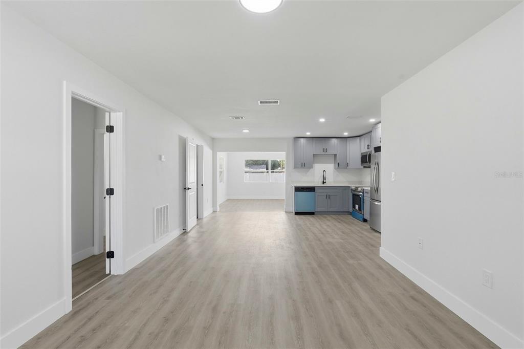 A bright, open-concept kitchen and living area features light wood-look flooring and grey cabinetry — 4075 38TH AVENUE N, ST PETERSBURG, FL