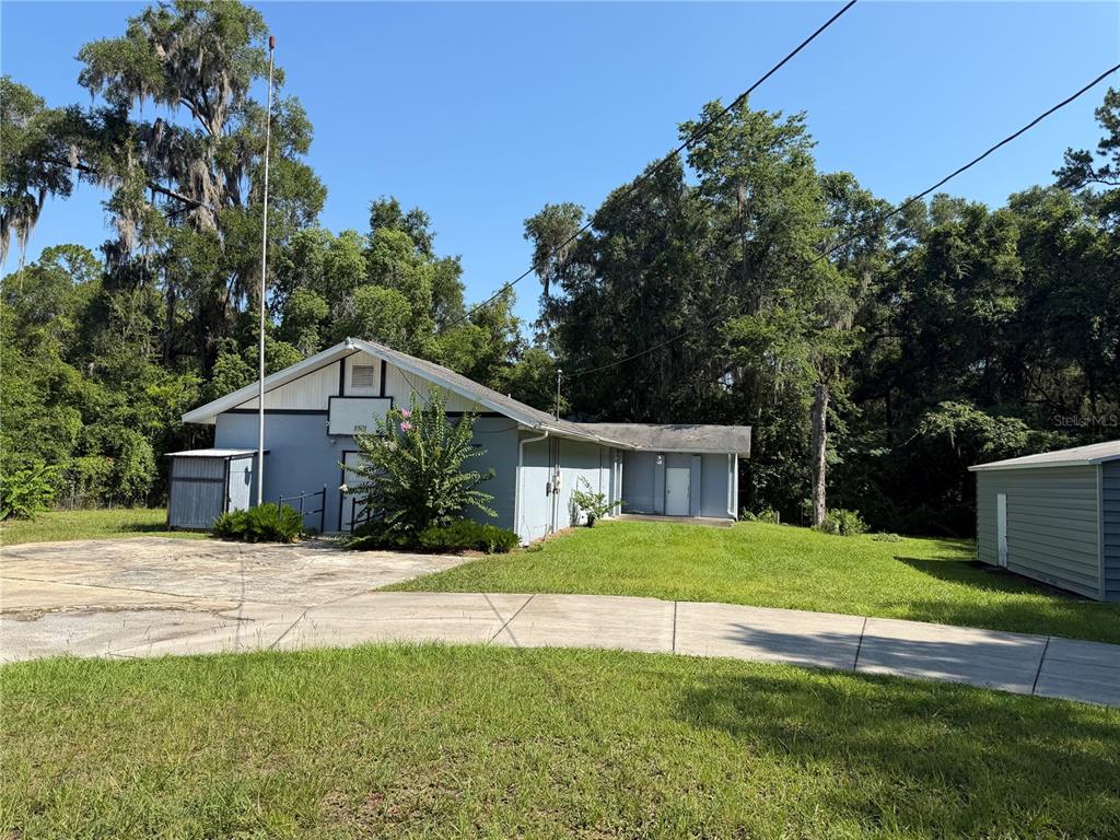 A light blue building with a gabled roof sits on a grassy lot with trees — 5561 NE 35TH STREET, SILVER SPRINGS, FL