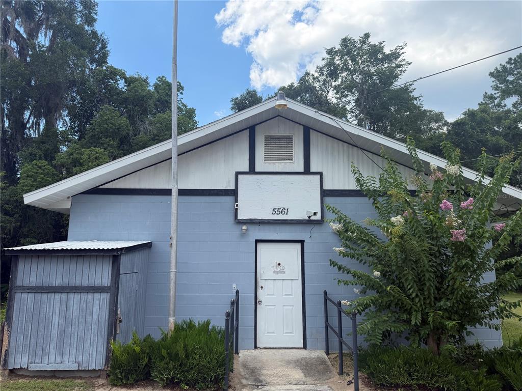 A light blue, single-story building with a white door, a metal roof, and a flagpole — 5561 NE 35TH STREET, SILVER SPRINGS, FL