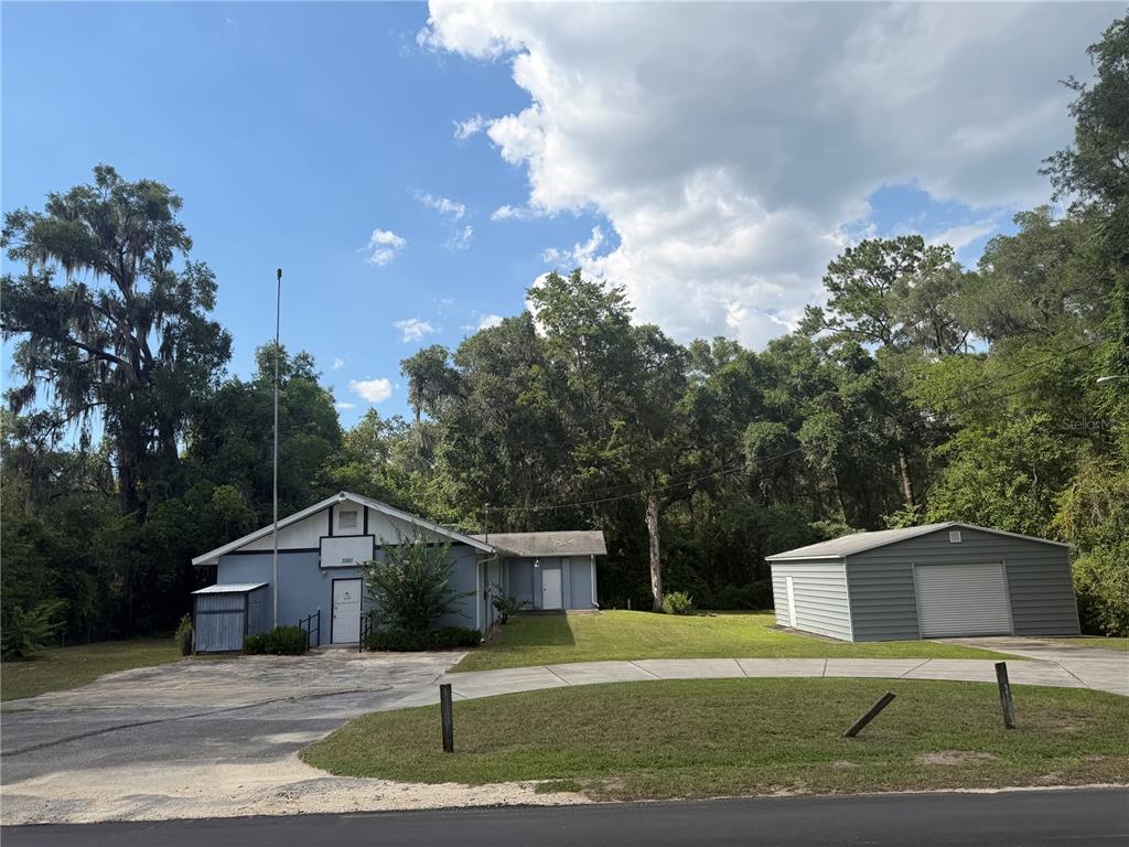 A light blue building with a detached garage sits on a grassy lot with trees — 5561 NE 35TH STREET, SILVER SPRINGS, FL