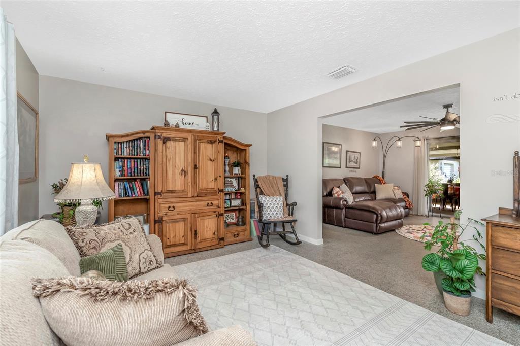 A brick house exterior features a covered porch, a wooden bench, and a gravel walkway — 12212 FLORAL LANE, THONOTOSASSA, FL