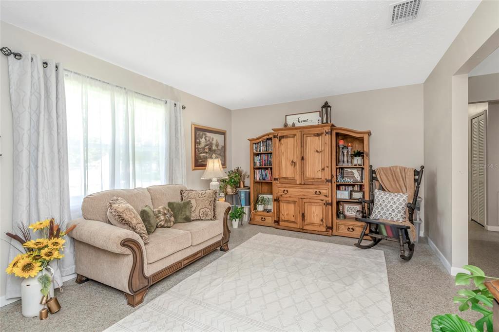 A living room features a beige sofa, a brown recliner, and a wooden entertainment center — 12212 FLORAL LANE, THONOTOSASSA, FL