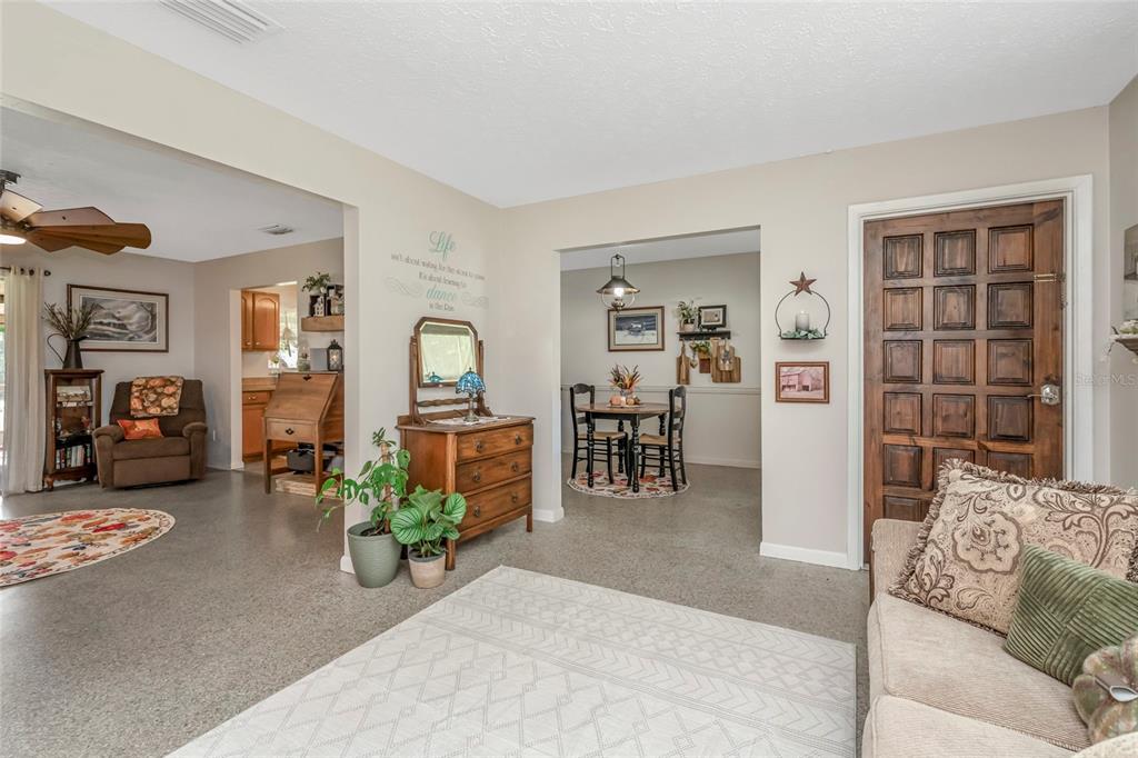 A living room with a tan sofa, carpeted floors, and an adjacent dining area — 12212 FLORAL LANE, THONOTOSASSA, FL