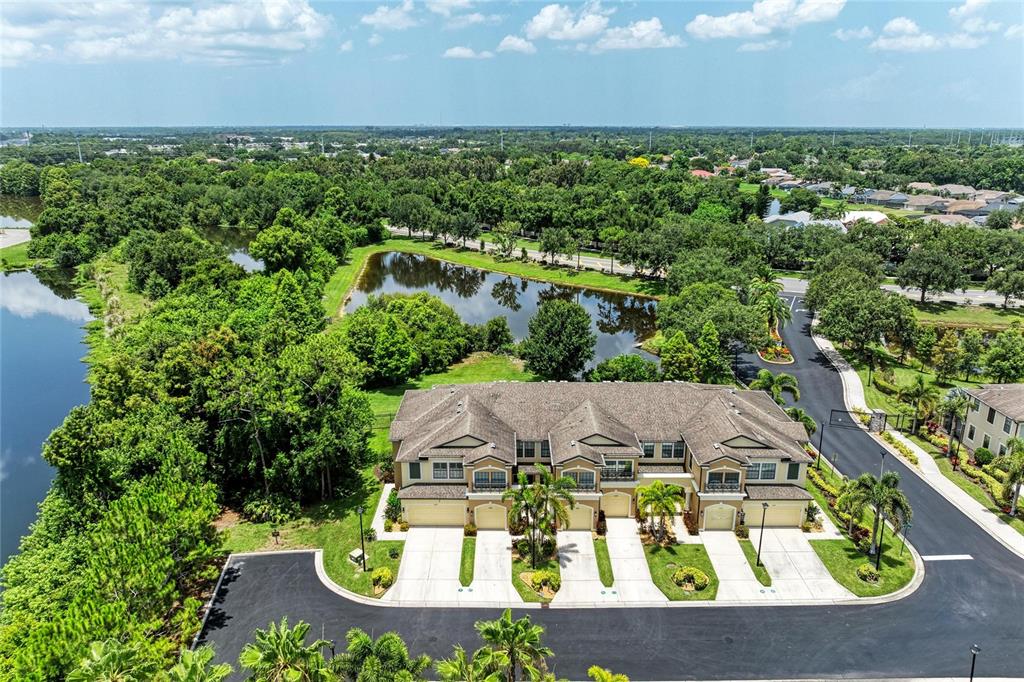 An aerial view shows a multi-unit townhouse building with a pond and surrounding trees — 5286 78TH ST CIRCLE E, BRADENTON, FL