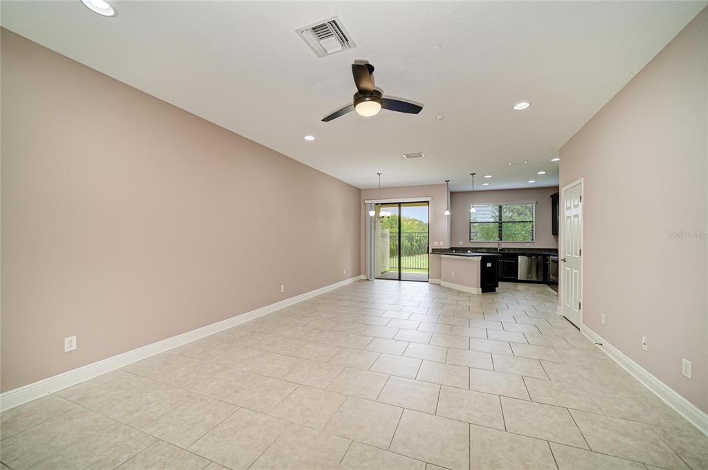 An open-concept living and dining area features light tile flooring and a kitchen with dark cabinetry — 5286 78TH ST CIRCLE E, BRADENTON, FL