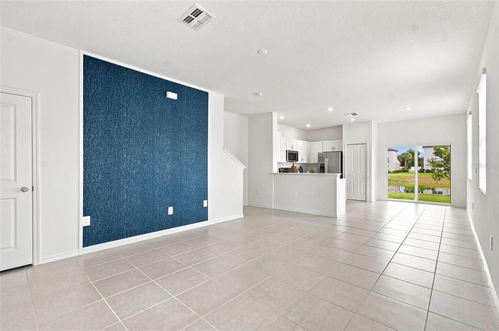 An open-concept living area features a blue accent wall, tile flooring, and a kitchen island — 36159 RISA MICHELE STREET, ZEPHYRHILLS, FL