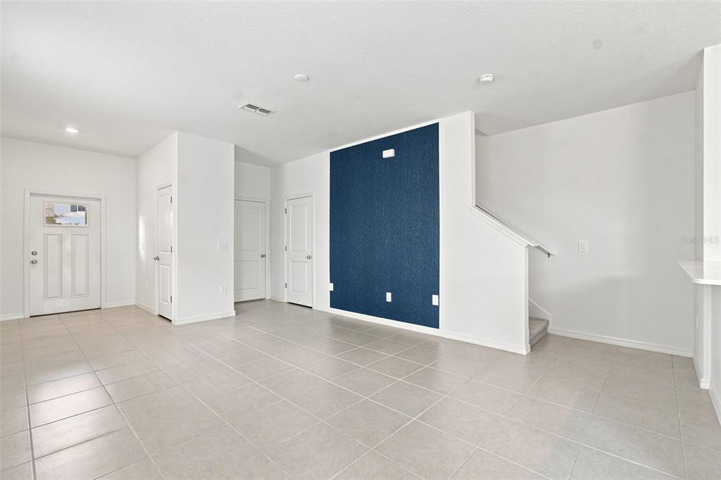 An interior view of a room with tile flooring, white walls, and a blue accent wall — 36159 RISA MICHELE STREET, ZEPHYRHILLS, FL