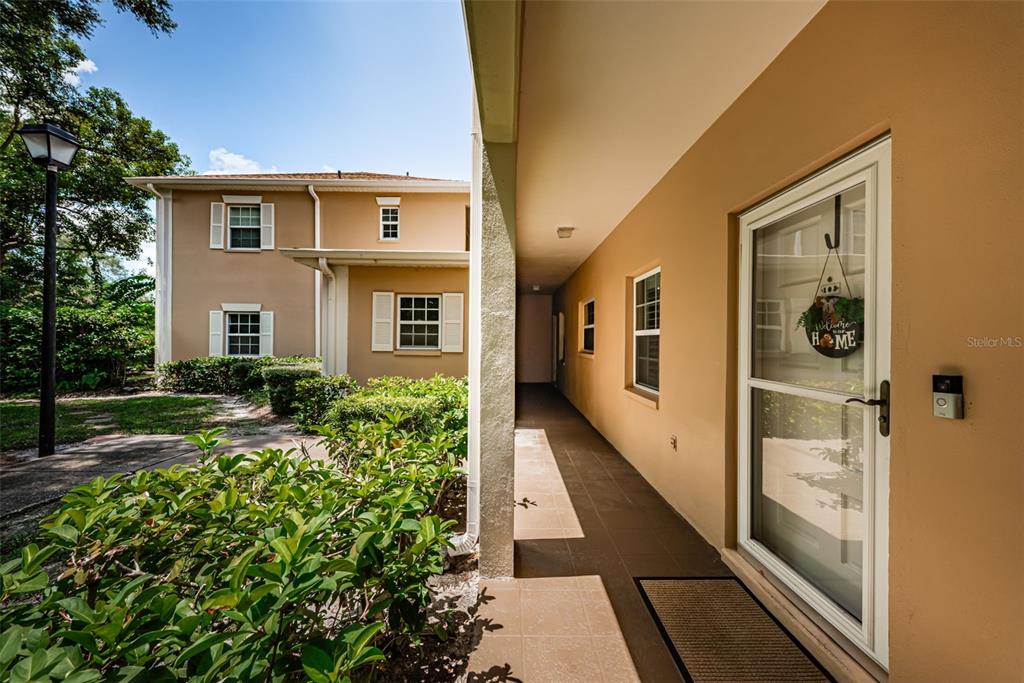 A covered walkway leads to a front door with a welcome sign beside a building — 8300 BARDMOOR BOULEVARD UNIT 103, SEMINOLE, FL