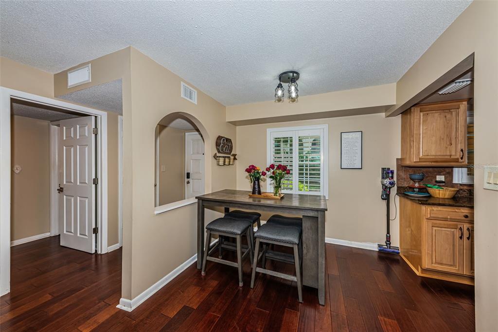 A dining area features a wooden table with two stools, dark flooring, and arched wall opening — 8300 BARDMOOR BOULEVARD UNIT 103, SEMINOLE, FL
