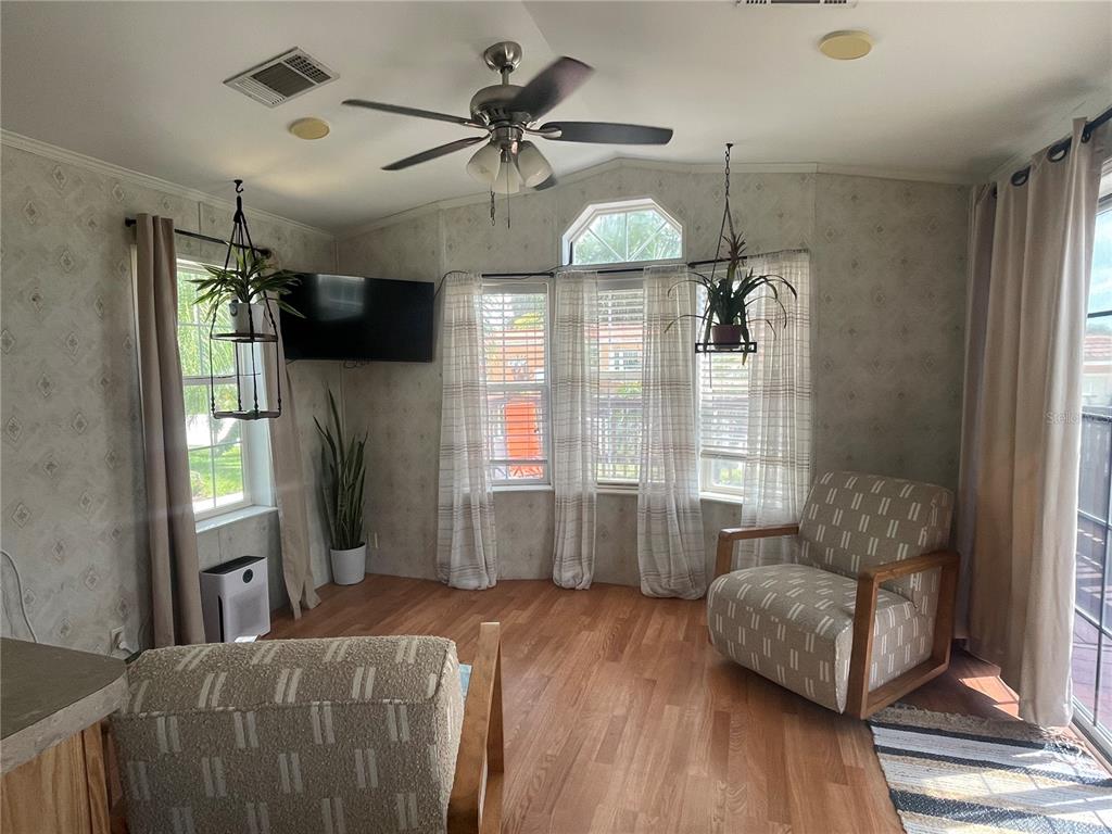 A living room features wood-look flooring, a ceiling fan, patterned wallpaper, and two armchairs — 21127 SAN PABLO DRIVE, LAND O LAKES, FL