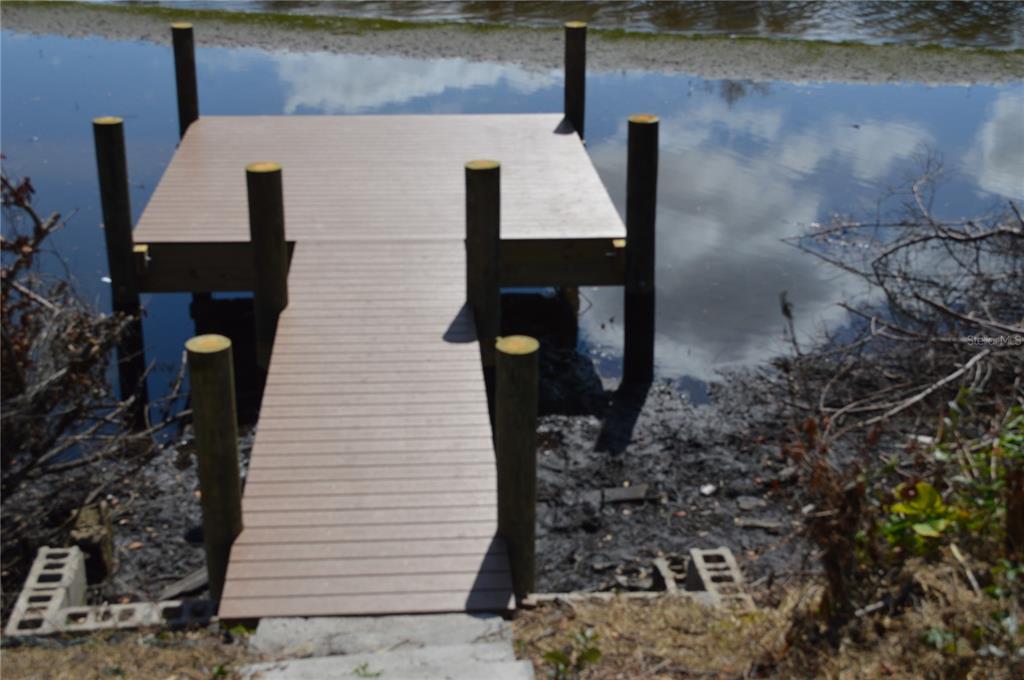 A wooden dock extends over a muddy shoreline into a calm body of water — 7023 PAYNE AVENUE, GIBSONTON, FL