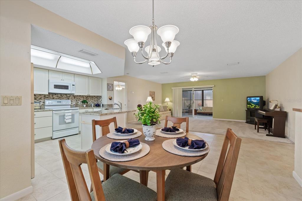 A dining area with a round table sits in front of an open kitchen and living room — 7329 FAIRWOOD AVENUE, NEW PORT RICHEY, FL