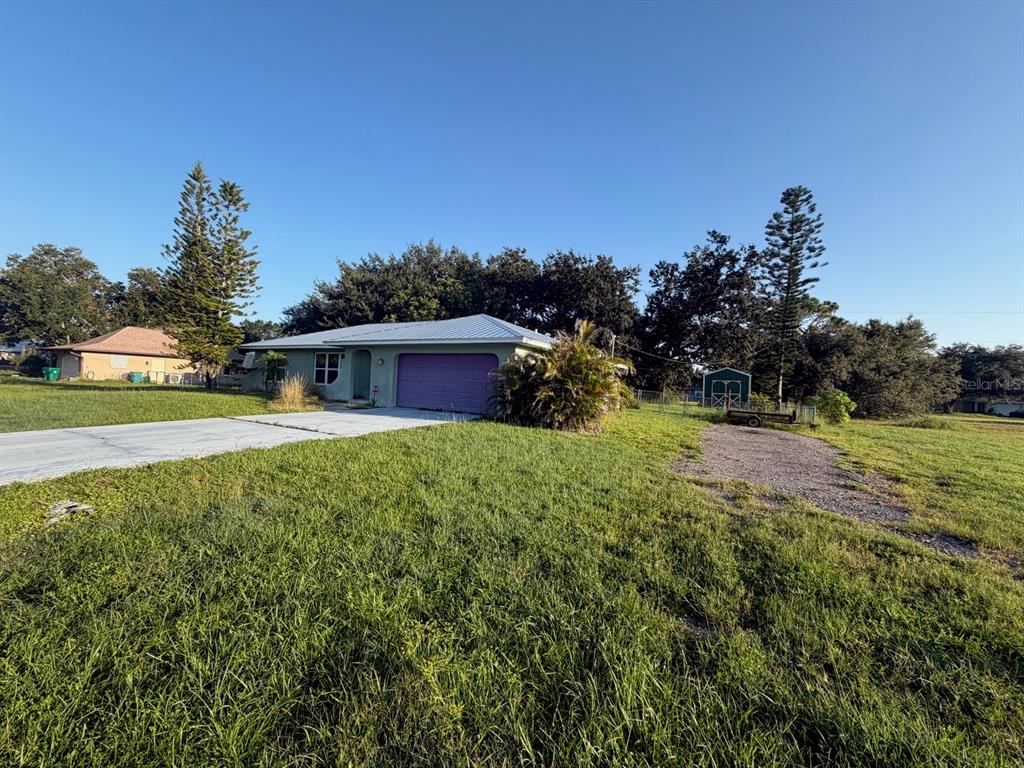 A single-story house with a purple garage door and a metal roof sits on grass — 30168 ALDER ROAD, PUNTA GORDA, FL