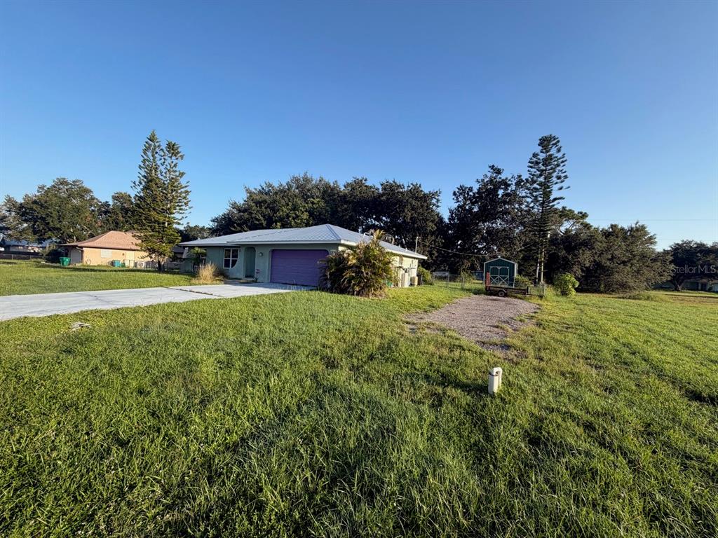 A single-story house with a purple garage door and a detached shed on a grassy lot — 30168 ALDER ROAD, PUNTA GORDA, FL