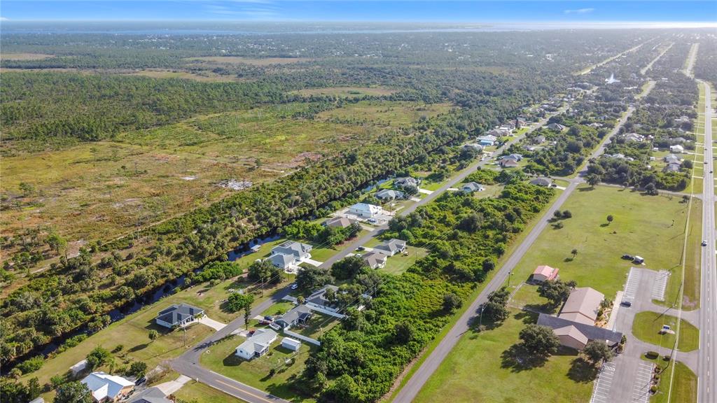 An aerial view shows a residential street lined with houses bordering a wooded canal area — 11024 EULER AVENUE, ENGLEWOOD, FL