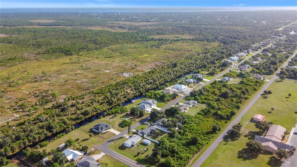 An aerial view shows a residential street lined with houses bordering a large, undeveloped field — 11024 EULER AVENUE, ENGLEWOOD, FL