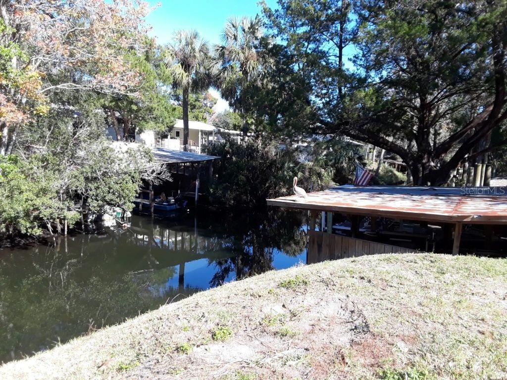 A canal view features two boat docks with a pelican perched on one roof — 8565 W DREW COURT, HOMOSASSA, FL
