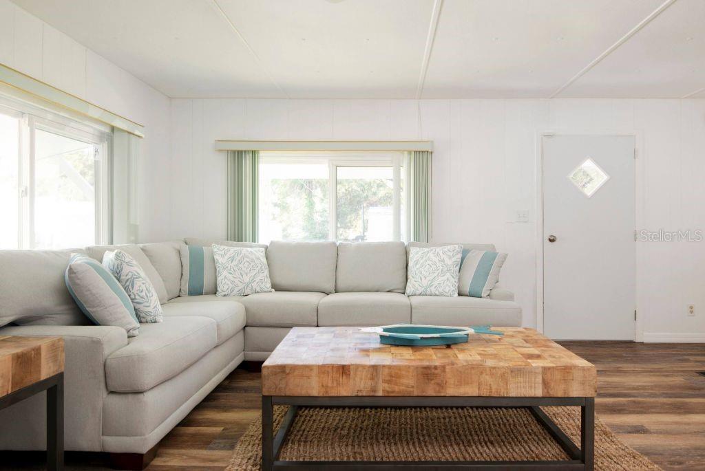 A living room features a light gray sectional sofa, a wooden coffee table, and wood-look flooring — 8565 W DREW COURT, HOMOSASSA, FL
