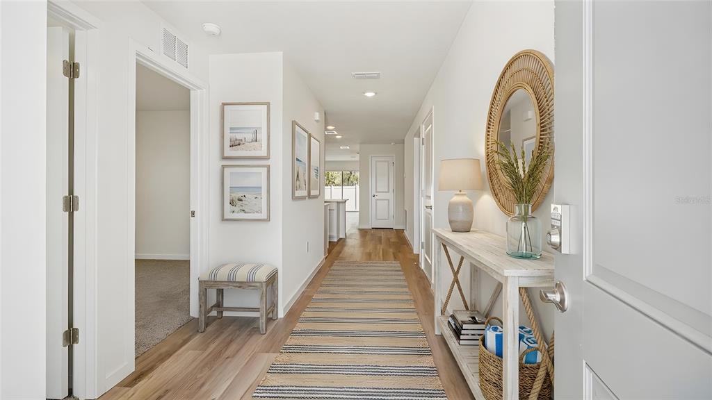 A bright entryway features a wood-toned console table, a striped runner, and coastal-themed wall art — 10157 SE 158TH LANE, SUMMERFIELD, FL