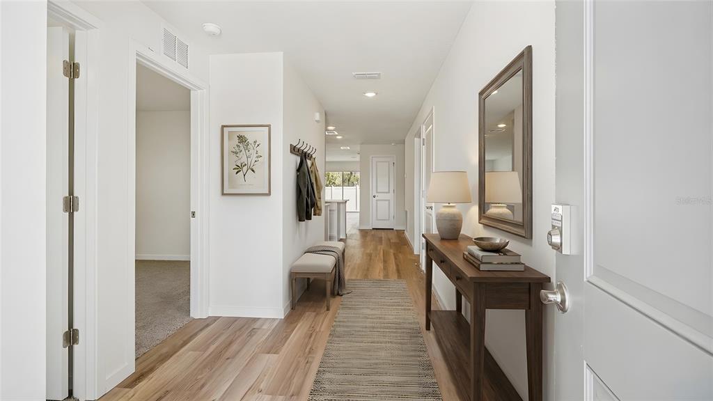A bright entryway features wood-look flooring, a console table with a mirror, and a bench — 10157 SE 158TH LANE, SUMMERFIELD, FL