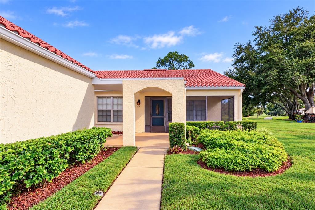 A concrete walkway leads to the front entrance of a house with a tiled roof — 978 MADRID DRIVE, PALM HARBOR, FL