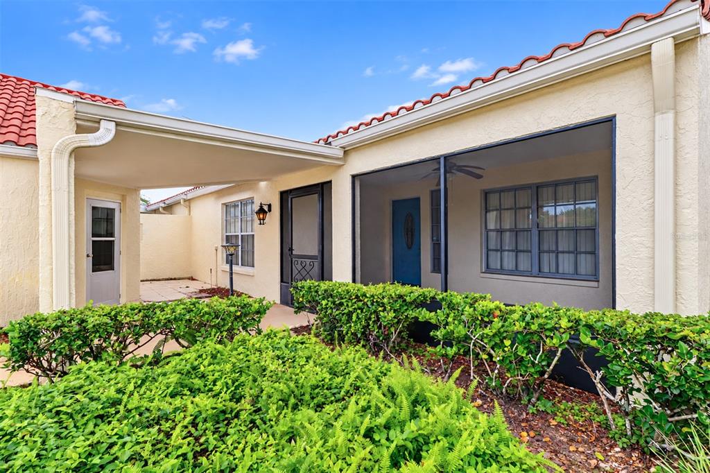 A house exterior featuring a covered entryway, a screened-in porch, and a red tile roof — 978 MADRID DRIVE, PALM HARBOR, FL